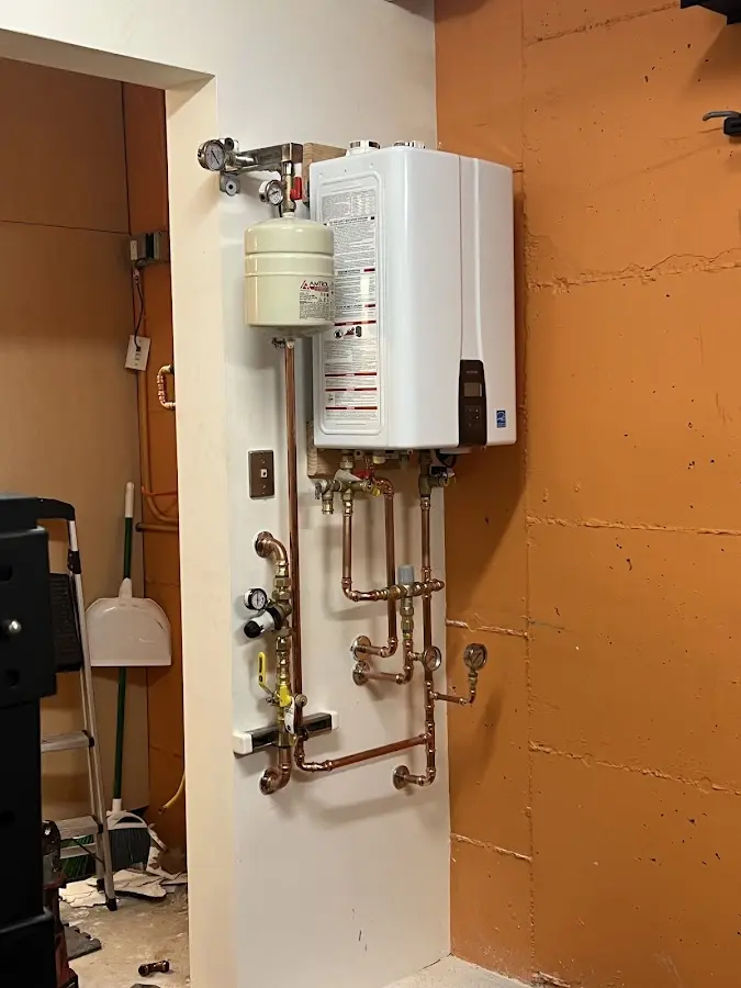 Plumbing technician inspecting water heater connections in Blackstone